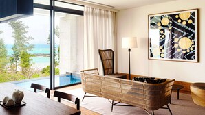 A modern room with a wooden dining table, wicker furniture, a floor lamp, and a large painting. - UMITO OKINAWA ONNASON (Onna)