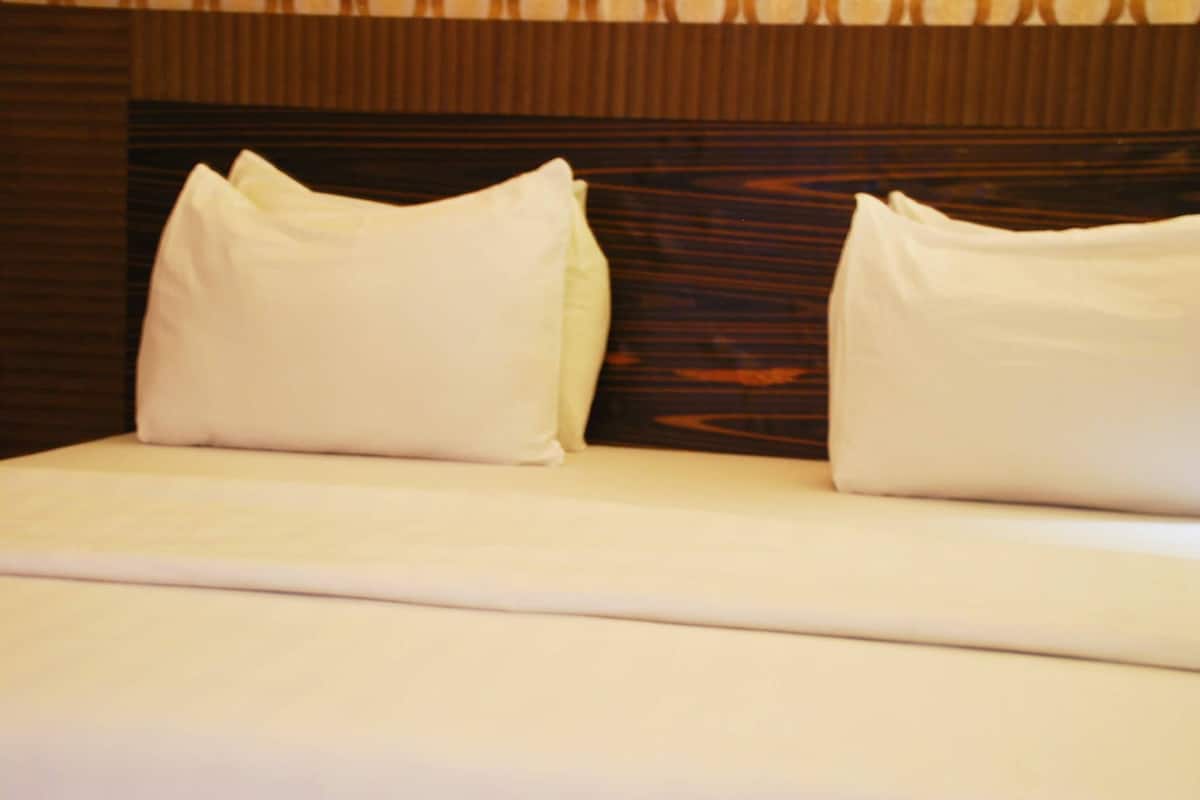 A neatly made bed with white linens and two pillows.