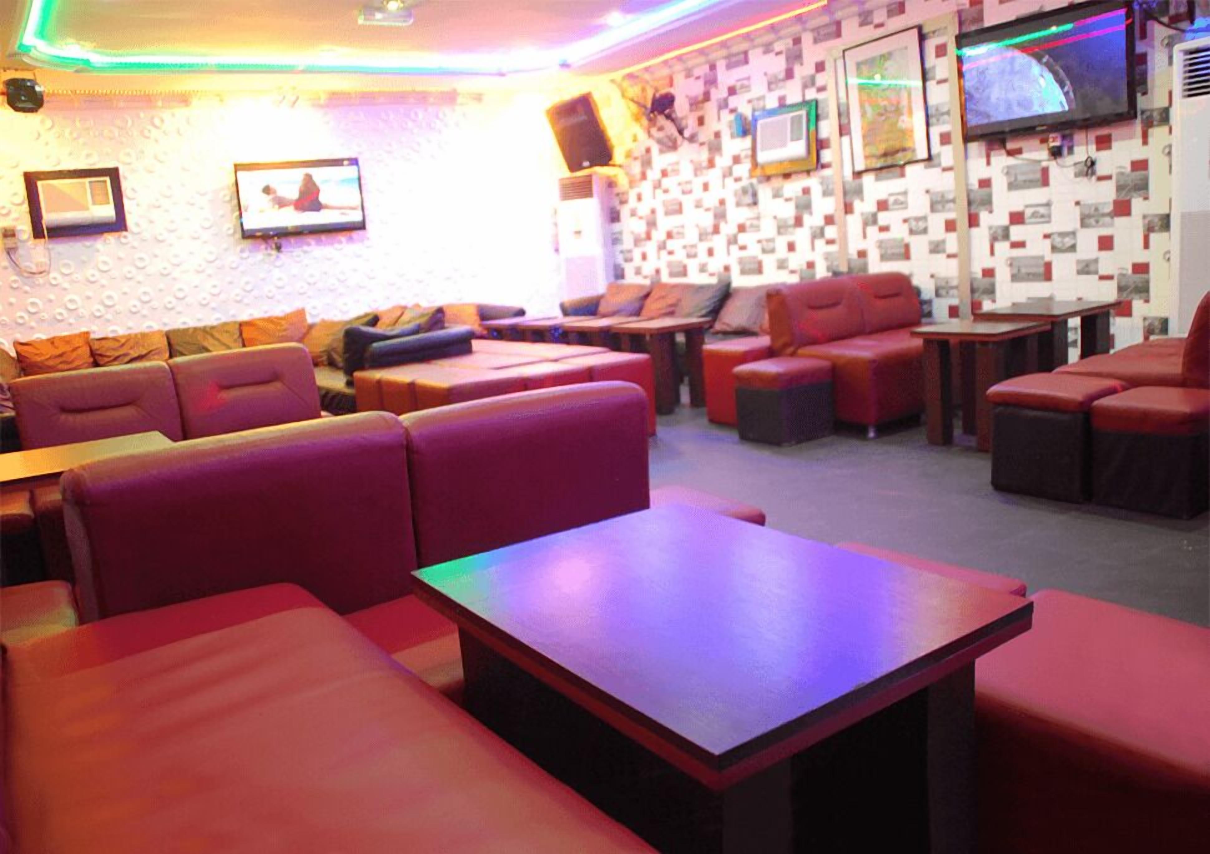 A modern lounge area with red seating, a flat-screen TV, and a patterned wall.