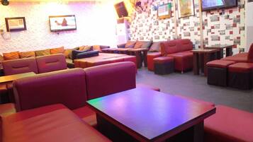 A modern lounge area with red seating, a flat-screen TV, and a patterned wall.