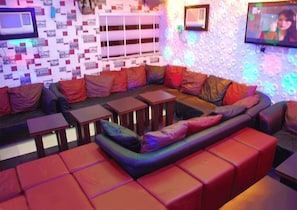 Un área de estar moderna con un sofá modular, mesas pequeñas y un papel tapiz estampado.