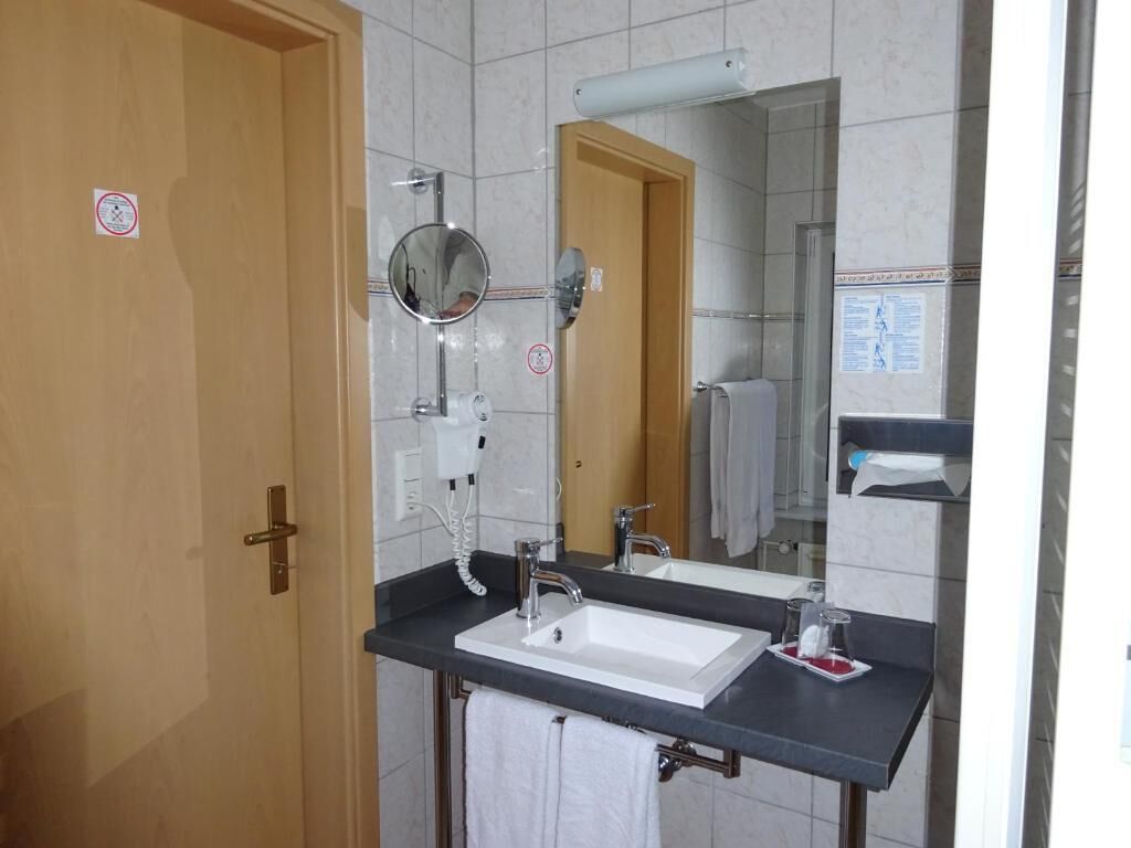 Une salle de bain avec un lavabo blanc, un miroir et une serviette accrochée au mur.