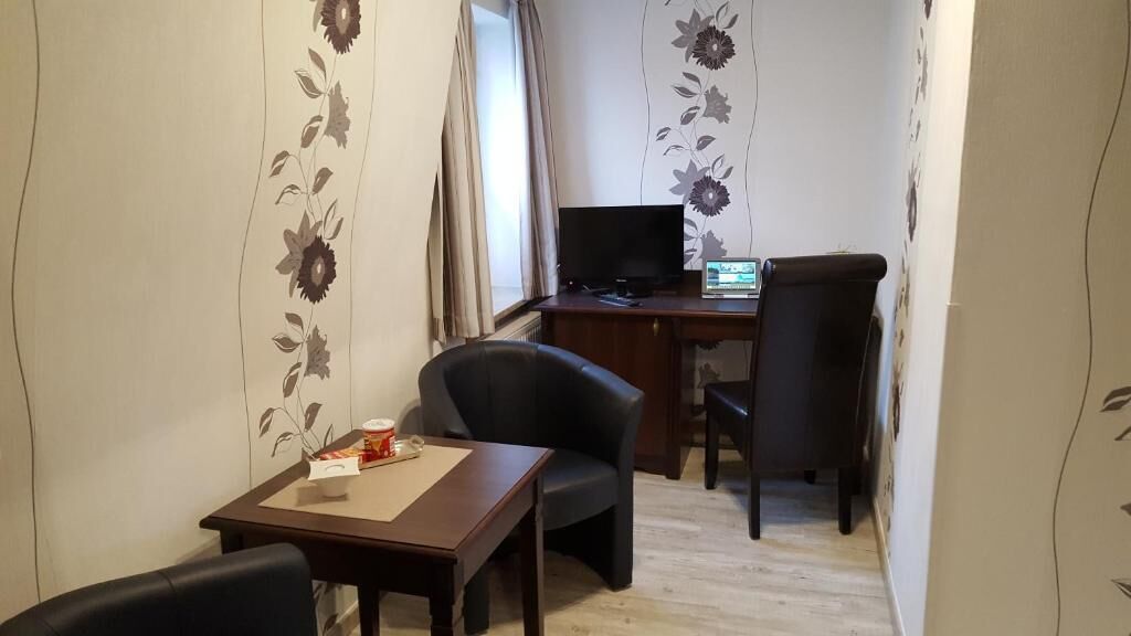 Ein kleiner, kompakter Raum mit Schreibtisch, Stuhl, Fernseher und Laptop.