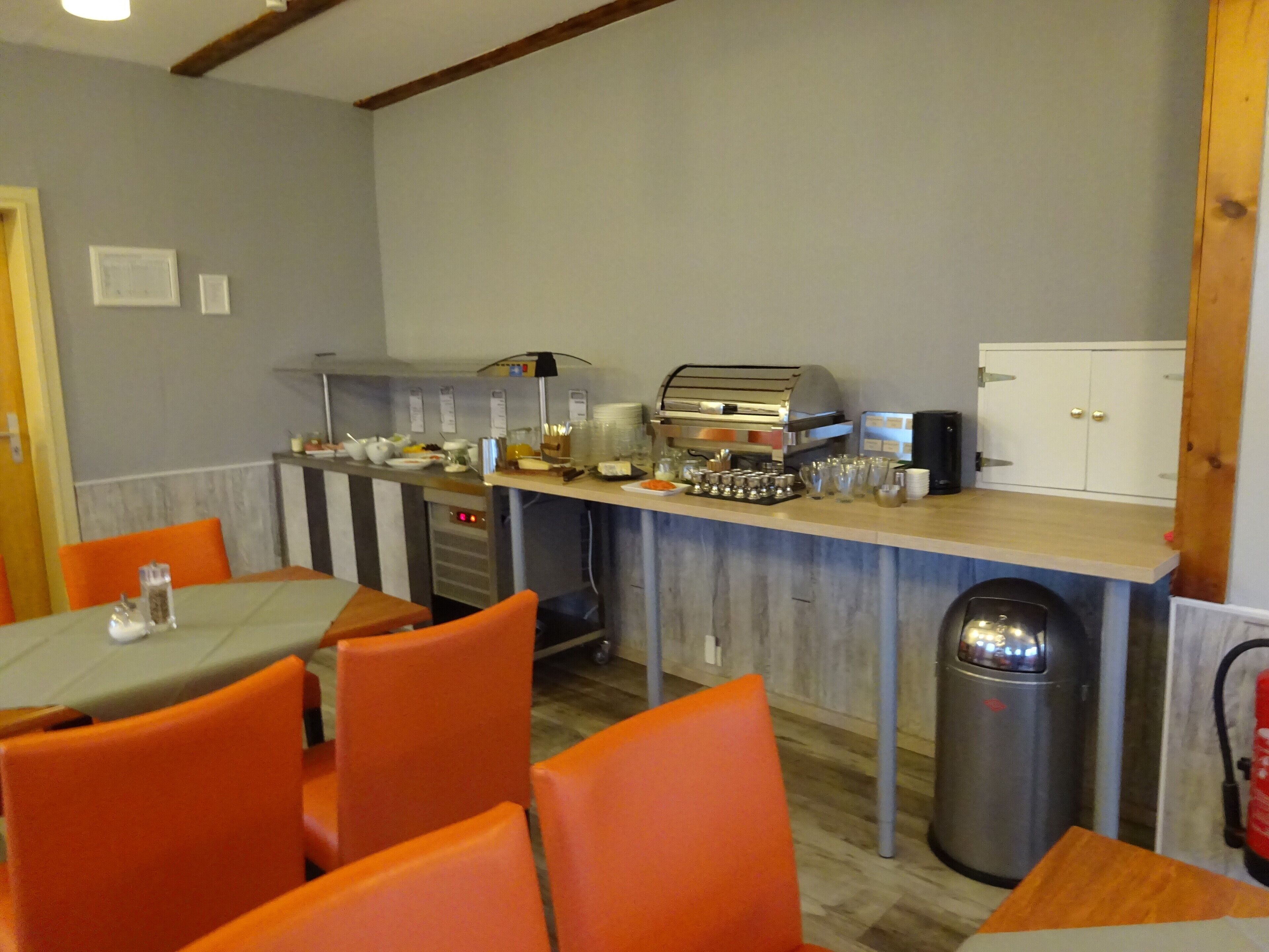 En morgenmadsbuffet med siddepladser og en kaffemaskine.