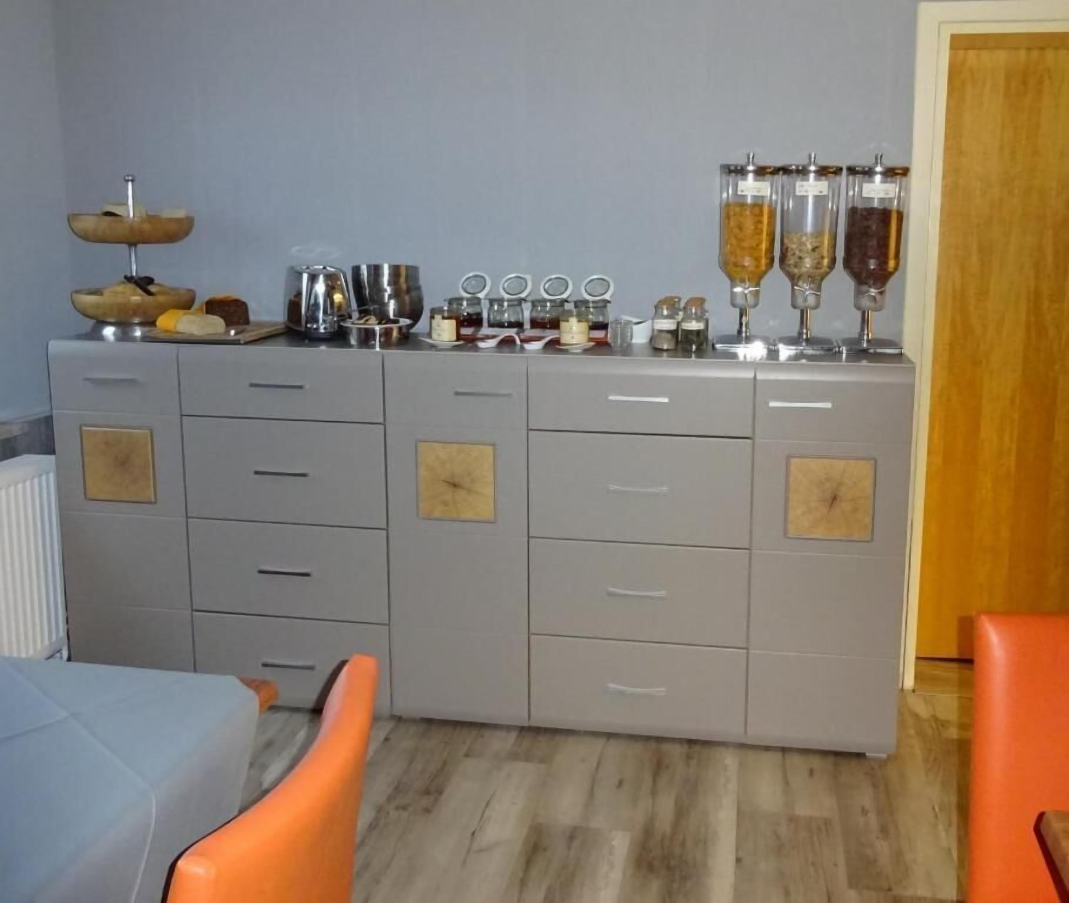 Eine Küche mit einem grauen Schrank, einer Holzkugel auf einem Sockel und Gewürzgläser auf der Arbeitsfläche.