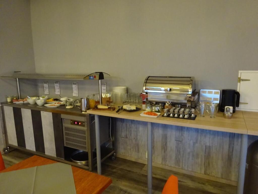 A self-service breakfast bar with various food items and beverages, a coffee machine, and a microwave.