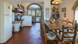 A spacious kitchen with a large dining table, wooden chairs, and a view through an arched doorway to a patio. - Beautiful  villa for 12 guests with private pool, WIFI, TV, terrace, pets allowed and panoramic ... (Scandicci)