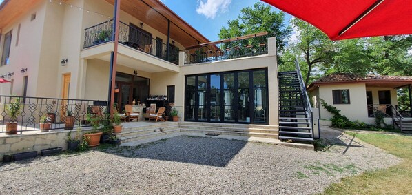 A two-story house with a balcony, outdoor seating area, and a staircase leading to the upper floor.