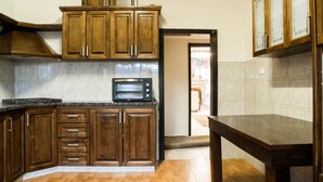 A kitchen with wooden cabinets, a microwave, and a tiled backsplash. - Old City Stylish 4BR by Ahlan Hospitality (Nazareth)