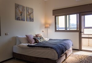 A bedroom with a bed, pillows, a lamp, and artwork on the wall. - Old City Stylish 4BR by Ahlan Hospitality (Nazareth)
