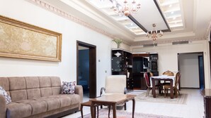 A spacious living room with a sofa, a coffee table, and a dining area with a table and chairs. - Old City Stylish 4BR by Ahlan Hospitality (Nazareth)