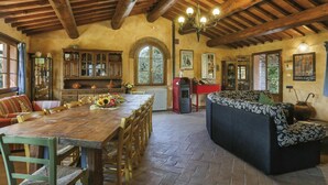 A rustic dining area with a wooden table and chairs, a sofa, and a chandelier.