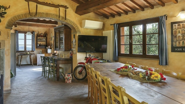 A rustic dining area with a wooden table, chairs, and a motorcycle.