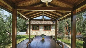 A covered outdoor dining area with a stone building in the background.