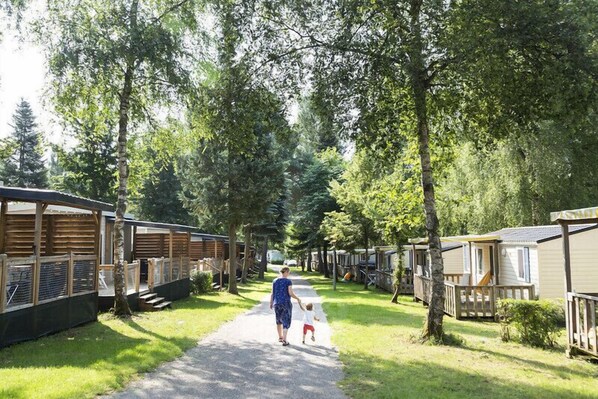 A pathway lined with mobile homes in a wooded area. - Hu Birkelt Village (Larochette)