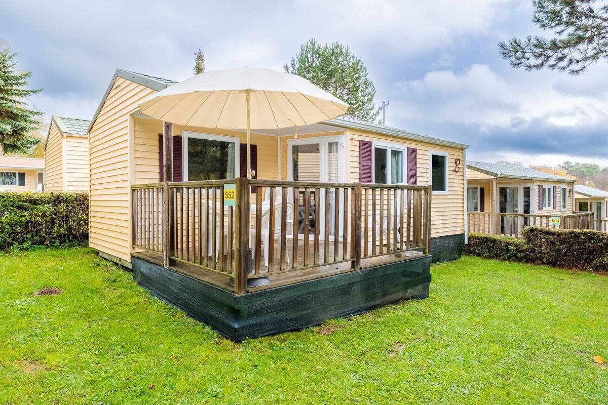 A single-story mobile home with a fenced deck, a covered porch, and a small outdoor area.