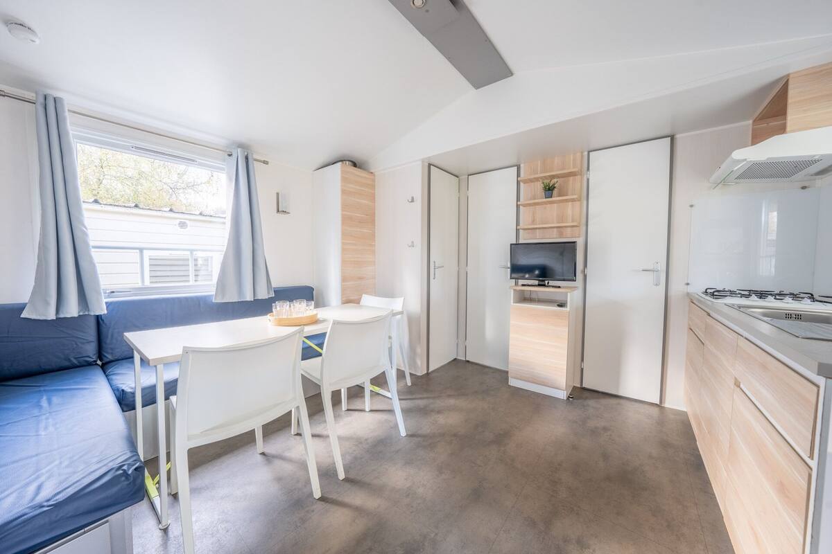 A compact kitchen with a dining area, a sofa, and a TV.