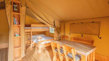 Ein gemütlicher Zeltenraum mit Etagenbett, einem Holztisch mit Stühlen, einem Bücherregal und einem Fenster.