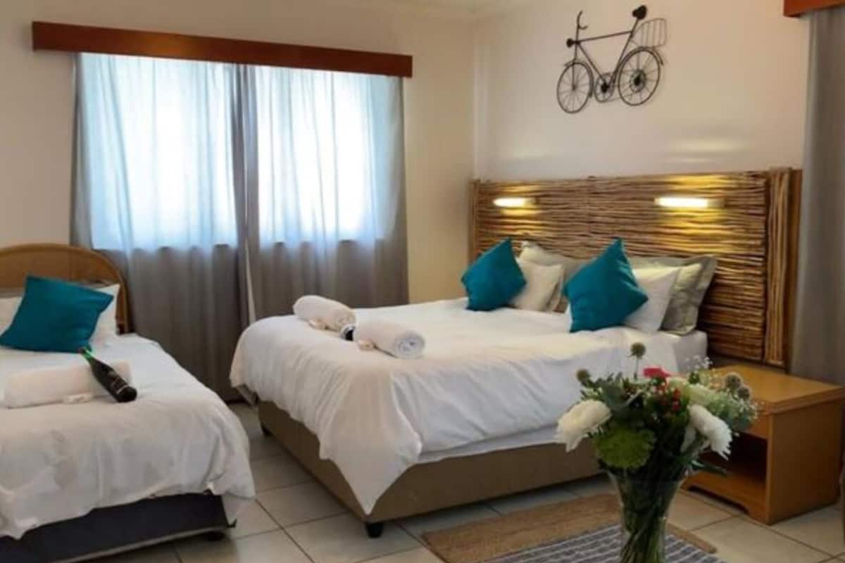 Habitación de hotel con dos camas, un adorno de bicicleta en la pared y un jarrón con flores.