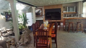 A dining area with a long table, chairs, and a bar counter. - The Lodge Strand (Cape Town)