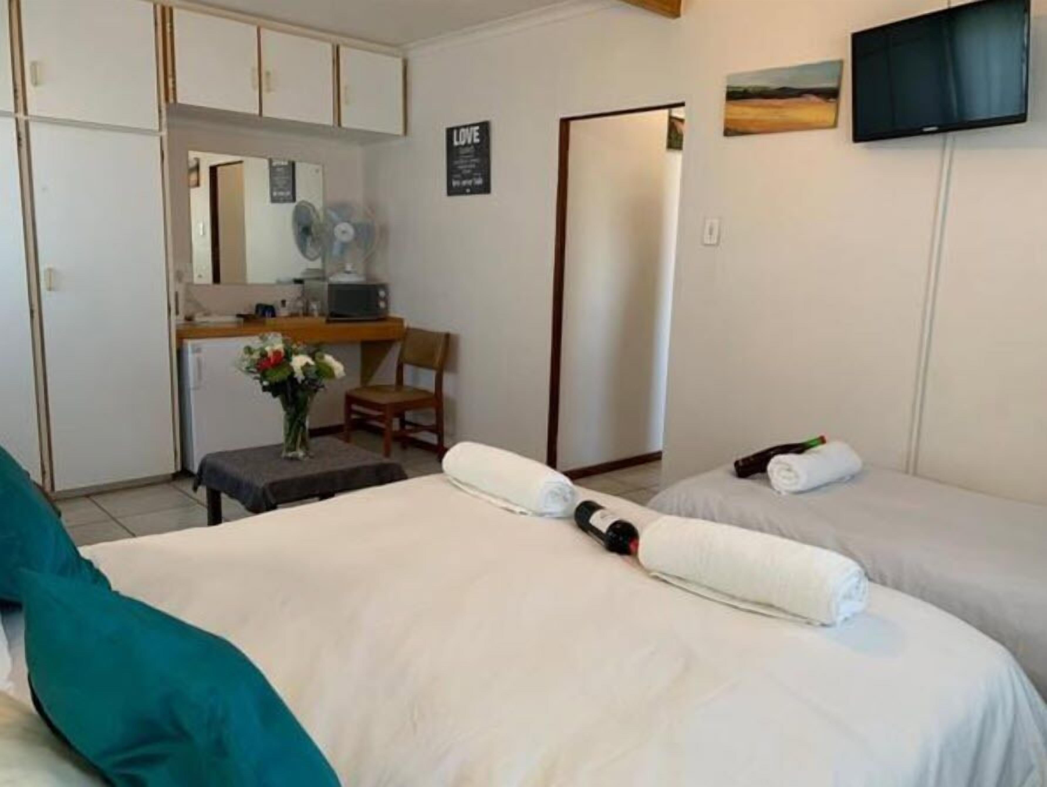 A hotel room with two beds, a desk with a chair, a TV, and a sign that says "LOVE".