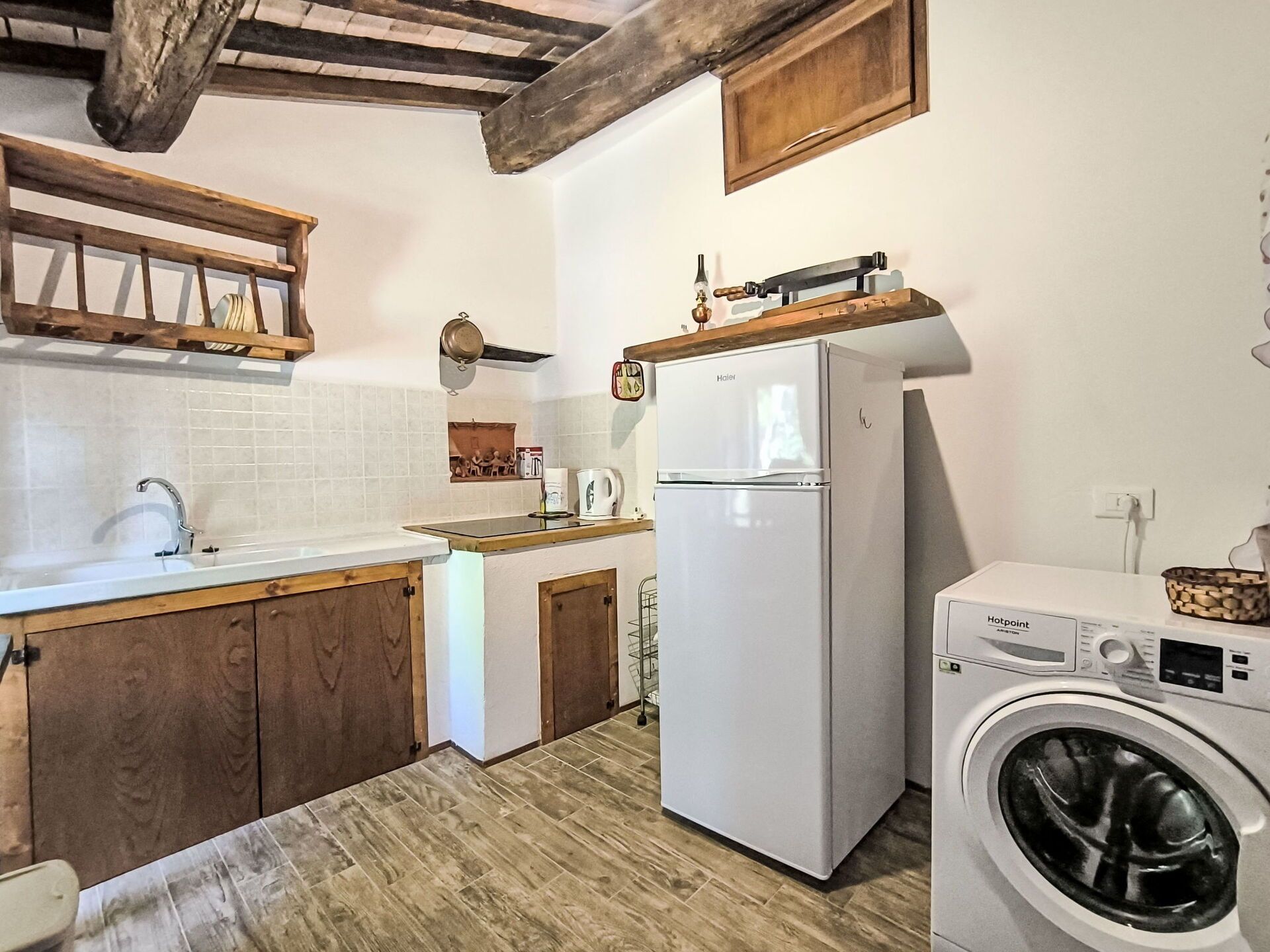Een kleine keuken met een koelkast, wasmachine en houten kastjes.