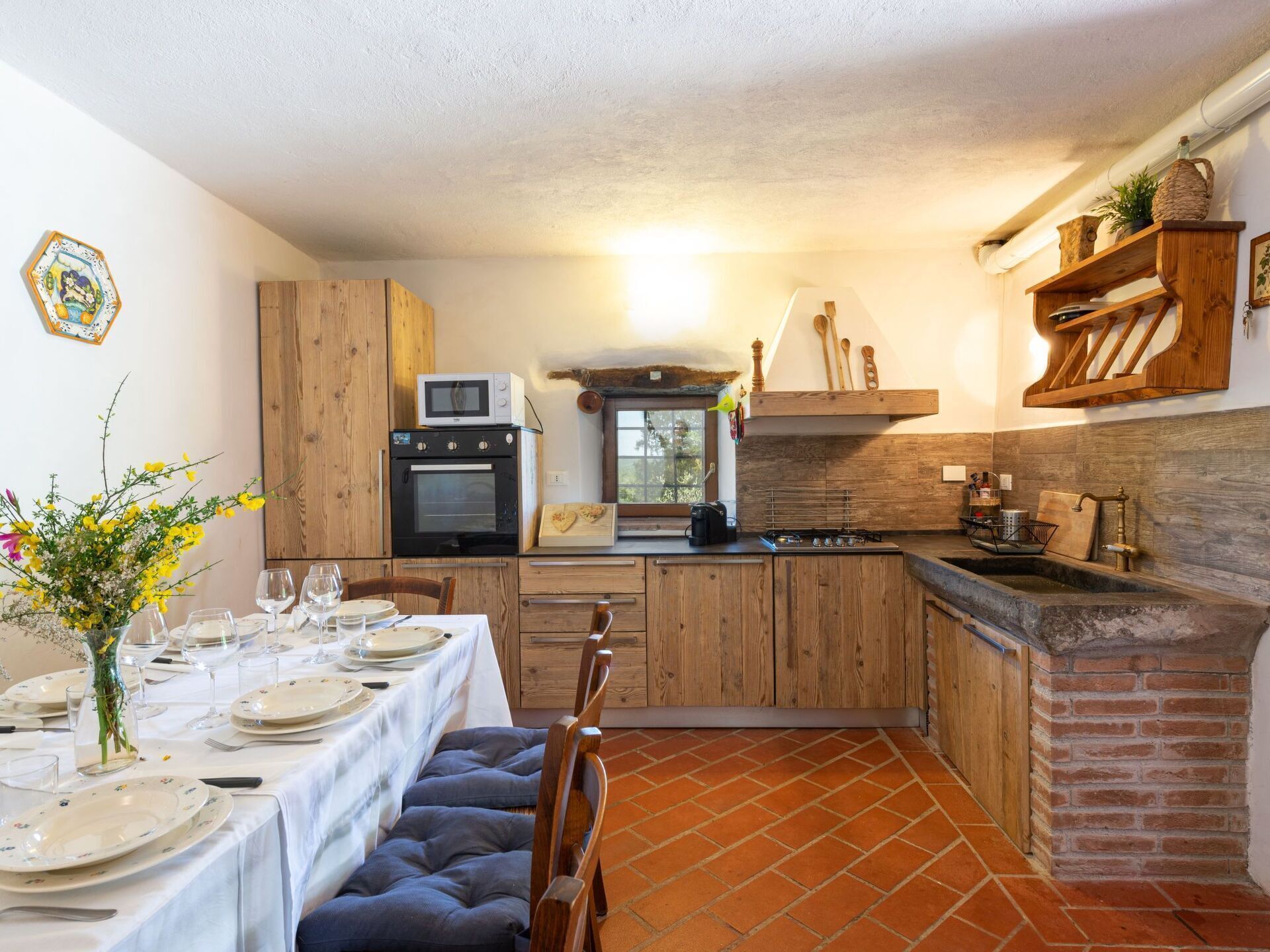 Una cocina compacta con armarios de madera, horno integrado, estufa y protector contra salpicaduras de ladrillo.