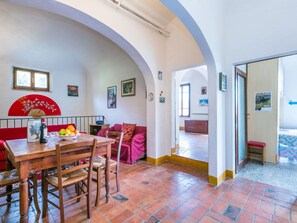 A dining area with a wooden table and chairs, a red sofa, and a fan. - Stunning private villa for 11 people with WIFI, TV, balcony and pets allowed (Sinalunga)