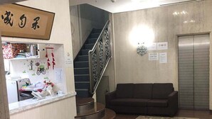 Un área de recepción con mostrador, escalera, sofá y ascensor.