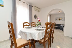 Un comedor con una mesa redonda, sillas de madera y un florero con flores.