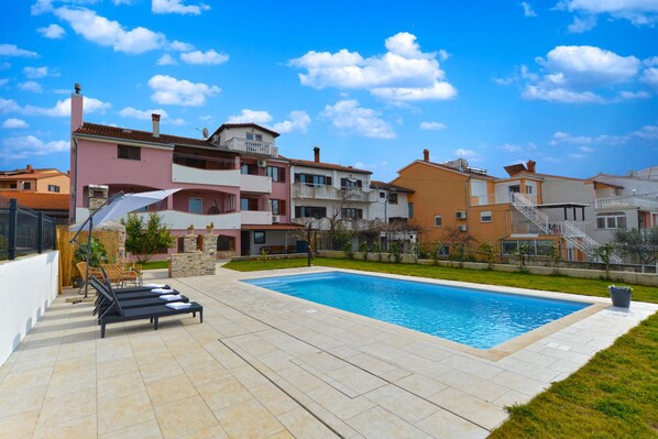 A residential area with a swimming pool, outdoor seating, and multi-story buildings.