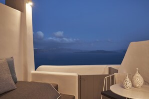 A balcony with a view of the sea, a white table with two decorative vases, and a sofa with patterned cushions. - Alisaris Caves (Santorini)