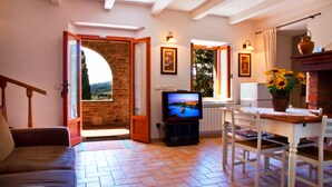 A cozy living room with a TV, a dining table, and a fireplace. - Welcome at Poggio Cantarello Country Home Tuscany (Chiusi)