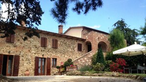 A stone building with a tiled roof, a staircase leading to an upper level, and a garden with potted plants and flowers. - Welcome at Poggio Cantarello Country Home Tuscany (Chiusi)