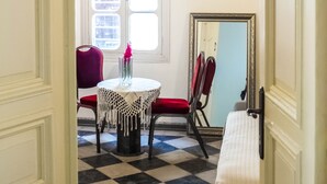 A room with a checkered floor, a round table with a vase, a mirror, and a red chair. - Heart of Old city 3BR by Ahlan Hospitality (Nazareth)
