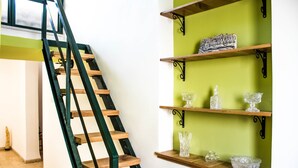 A staircase with wooden steps and black metal railings, flanked by green walls and wooden shelves holding glassware and a decorative item. - Heart of Old city 3BR by Ahlan Hospitality (Nazareth)