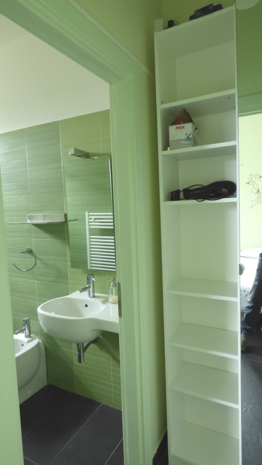 Een badkamer met een wastafel, spiegel en een witte schapunit.