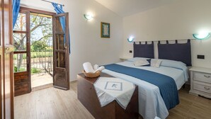 Ein Schlafzimmer mit Bett, Nachttischen, einem Schminktisch und einem Schrank mit Vorhängen am Fenster.