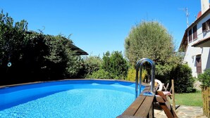 Ein klarer, blauer Swimmingpool mit einer Holzterrasse und einer Metallleiter.