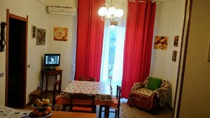 A dining area with a table, chairs, a television, and a window with red curtains. - Sea Levanto and Cinque Terre Calm, Cool, Freedom,for Children and pet Parking (Carrodano)
