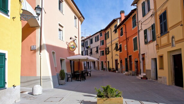 A narrow street with buildings on either side, outdoor seating, and a planter with plants. - Sea Levanto and Cinque Terre Calm, Cool, Freedom,for Children and pet Parking (Carrodano)