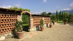 Un cortile con muro in pietra, piante in vaso e vista sulle montagne.