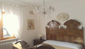 A bedroom with a wooden bed, a chandelier, a nightstand, a lamp, and artwork on the walls. - Villa In Lucca Placed in a Residential Area, all Services Nearby (Capannori)