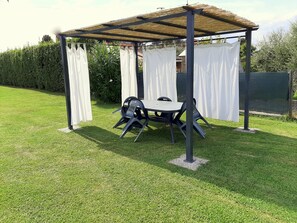 A gazebo with a table and chairs, surrounded by a well-maintained lawn and a hedge. - Villa In Lucca Placed in a Residential Area, all Services Nearby (Capannori)