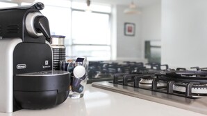 Une cuisine équipée d’une machine à café, d’un verre d’eau et d’une cuisinière à gaz.
