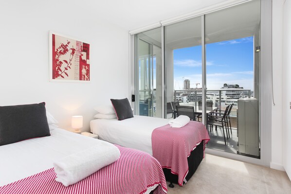 A hotel room with two beds, a balcony with a city view, and a large window. - As the Sun Sets (Zetland)