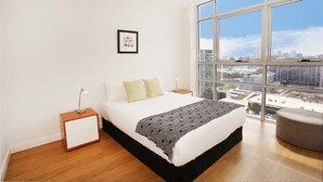 A modern bedroom with a large window, a bed, a nightstand, and a framed picture on the wall. - Moore to See (Zetland)