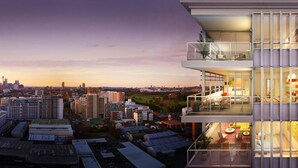 A modern building with a glass facade, multiple balconies, and a cityscape view in the background. - Moore to See (Zetland)
