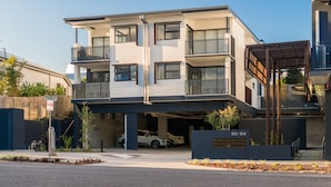 A modern multi-story residential building with a garage, balconies, and a covered outdoor area. - Oxford Steps (Bulimba)