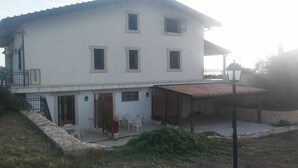 A two-story house with a covered patio area, a small garden, and a street lamp. - Apartment in Countryside Villa With Pool Within the Se Sicilian Barocco Area (Ragusa)